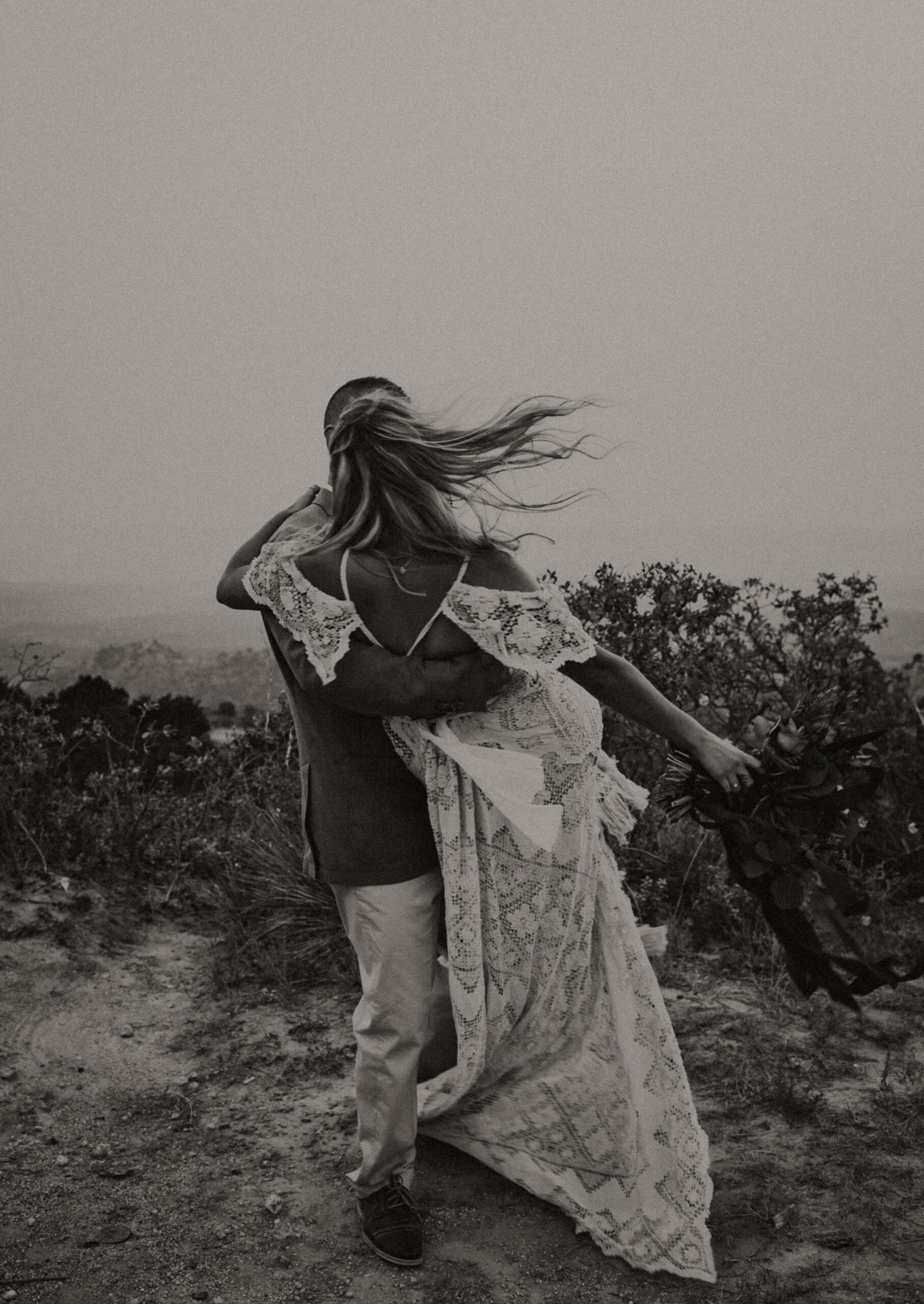 black and white image of a man holding a woman while twirling around the canyon for their elopement photoshoot. Texas based destination elopement photographer