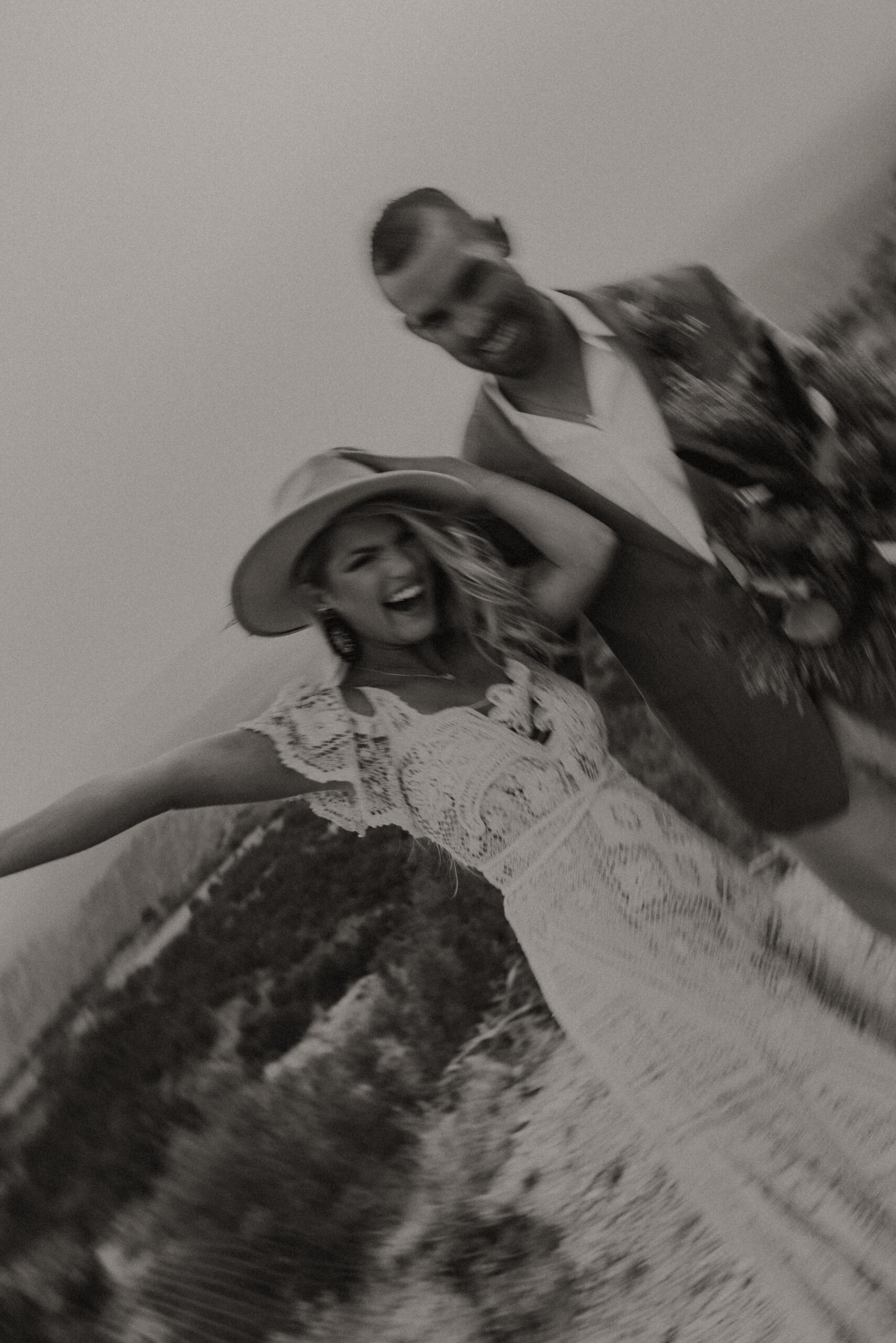 burry black and white photo of bride and groom smiling and laughing while on a canyon for their elopement photoshoot. Adventure destination elopement photography in Texas