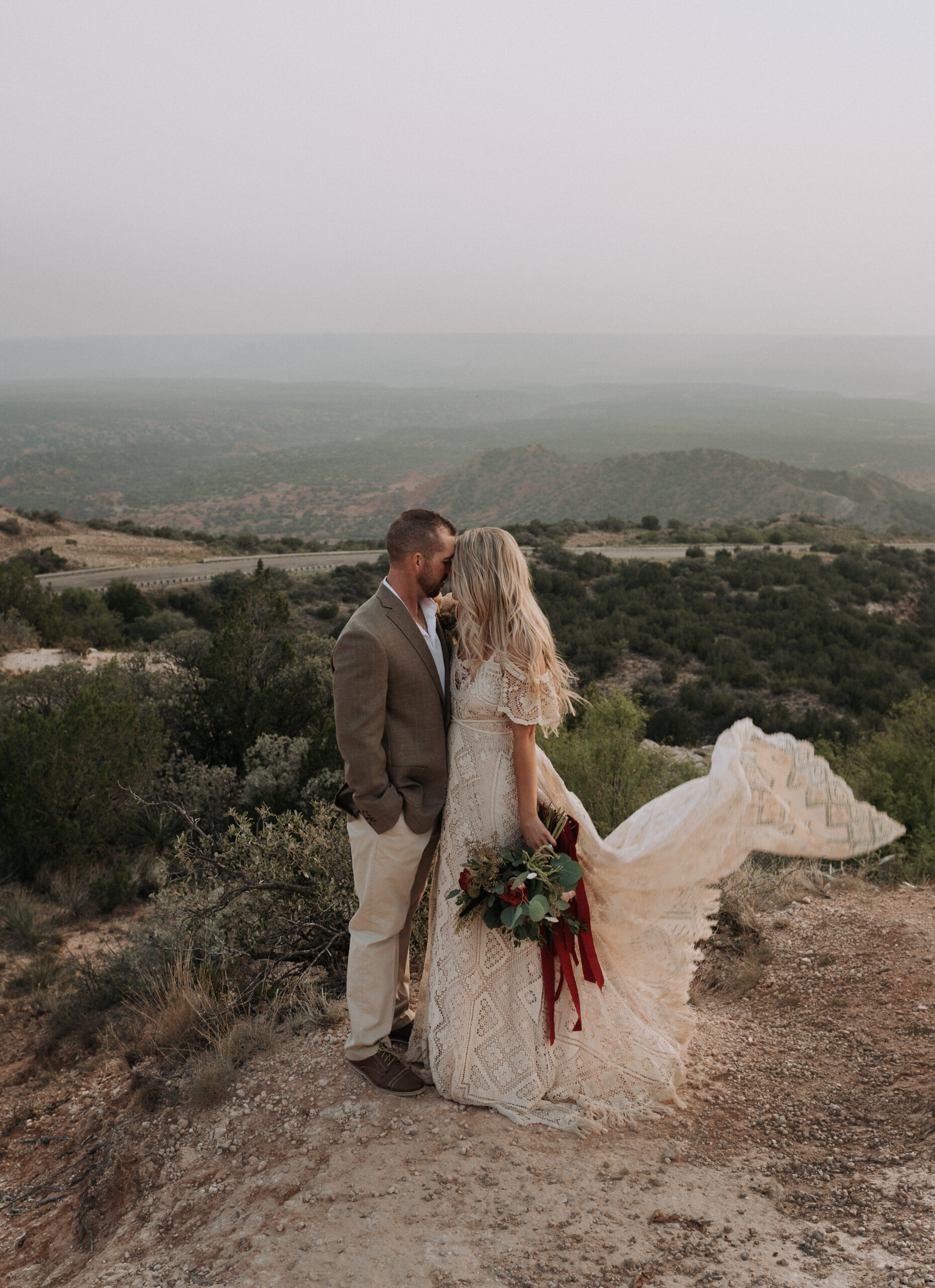 man and woman kissing on a canyon while overlooking a forest in Texas. Elopement photographer in Texas