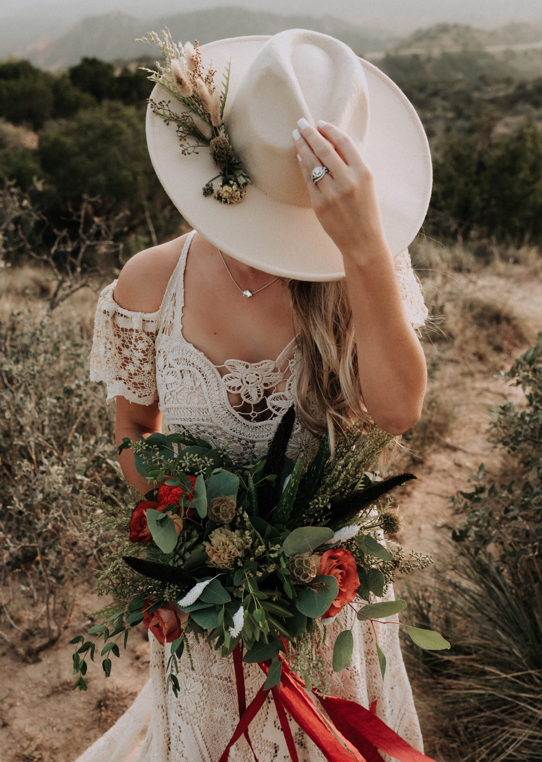 woman holding a hat while holding a bouquet of flowers in the other hand. elopement photos in the canyons from a destination elopement photographer 