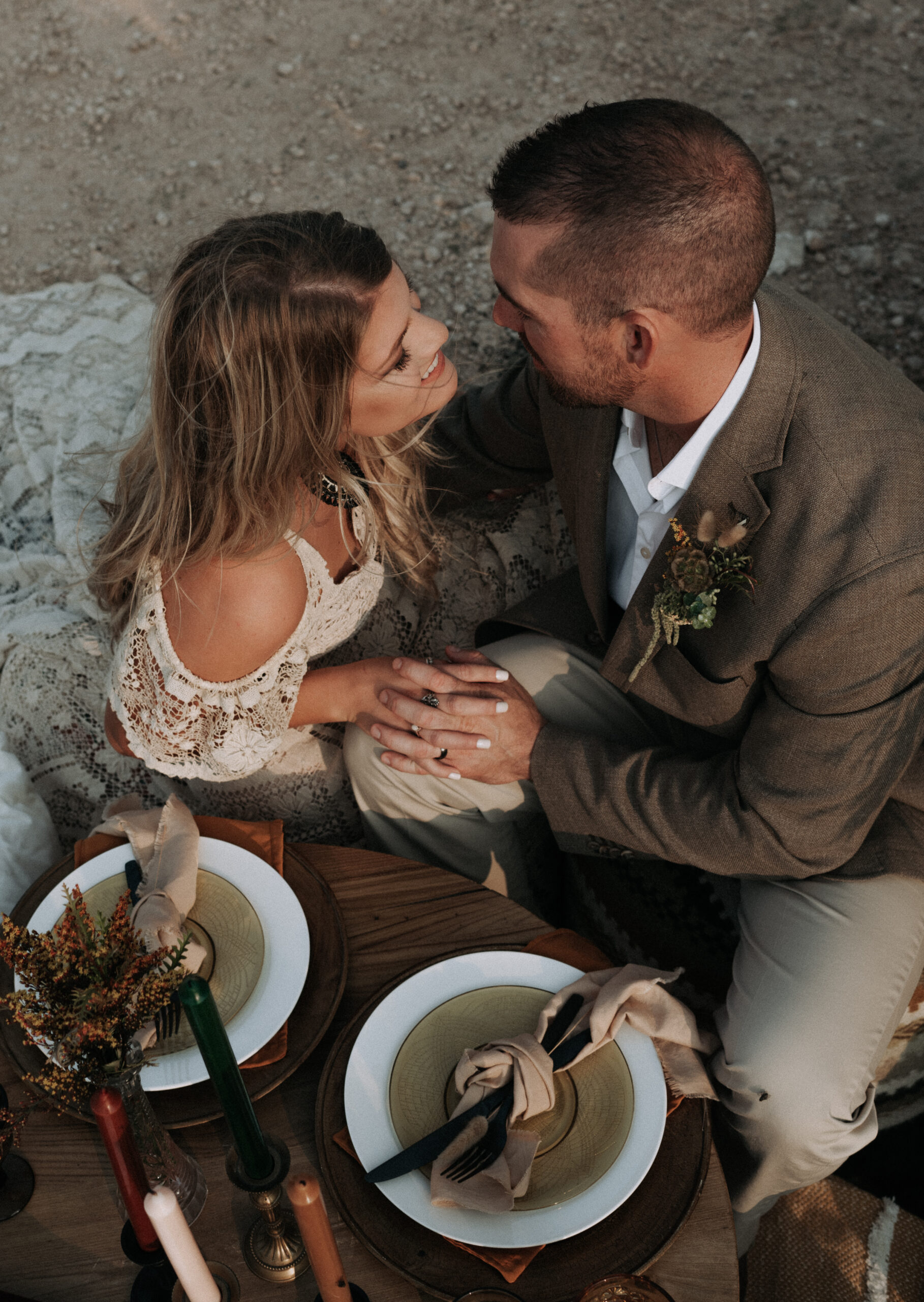 woman holding mans hand while sitting on floor at picnic for their elopement ceremony