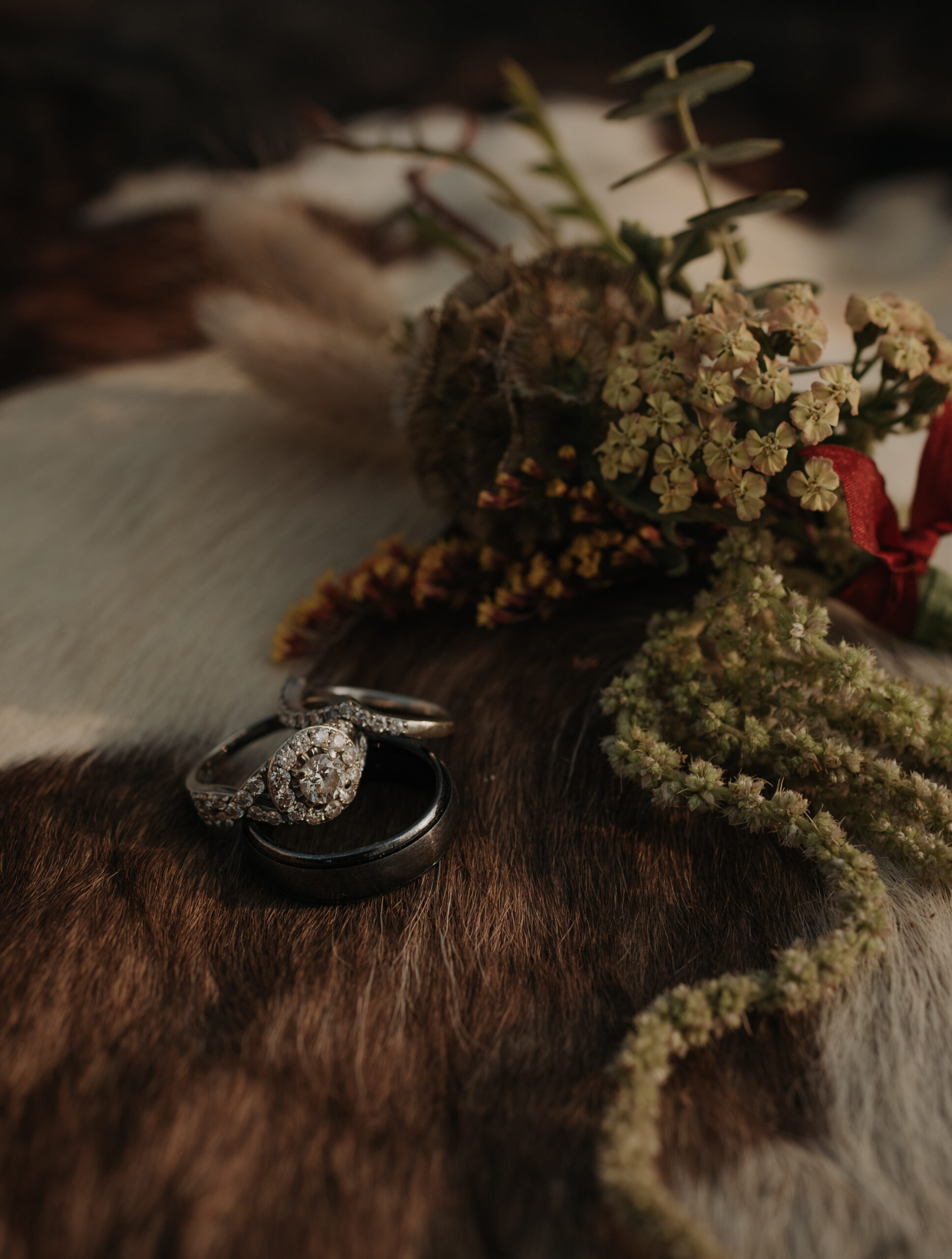 ring detail photo with flowers that have desert tones and a cow hide backdrop. elopement photographer in texas