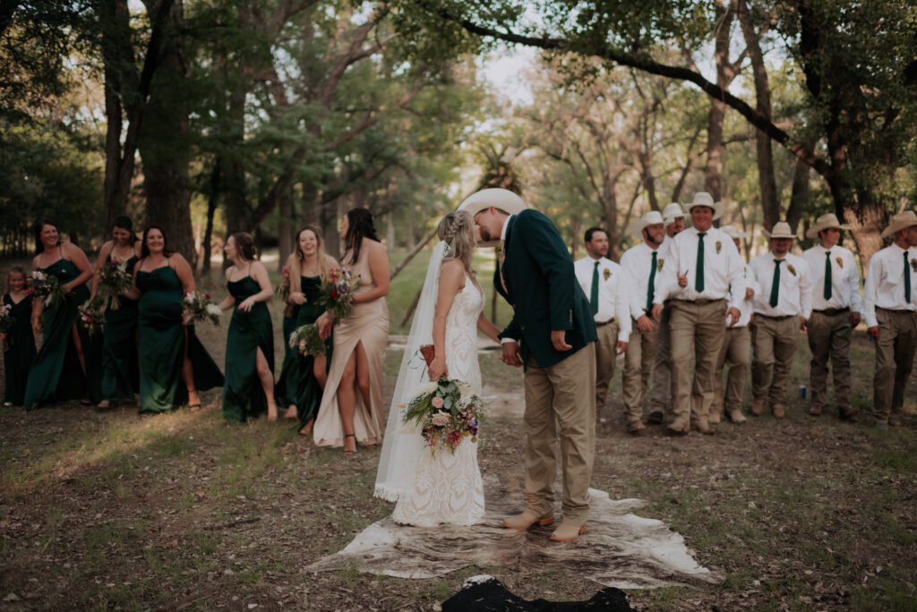 bride and groom kissing while with bridal party, texas wedding photographer