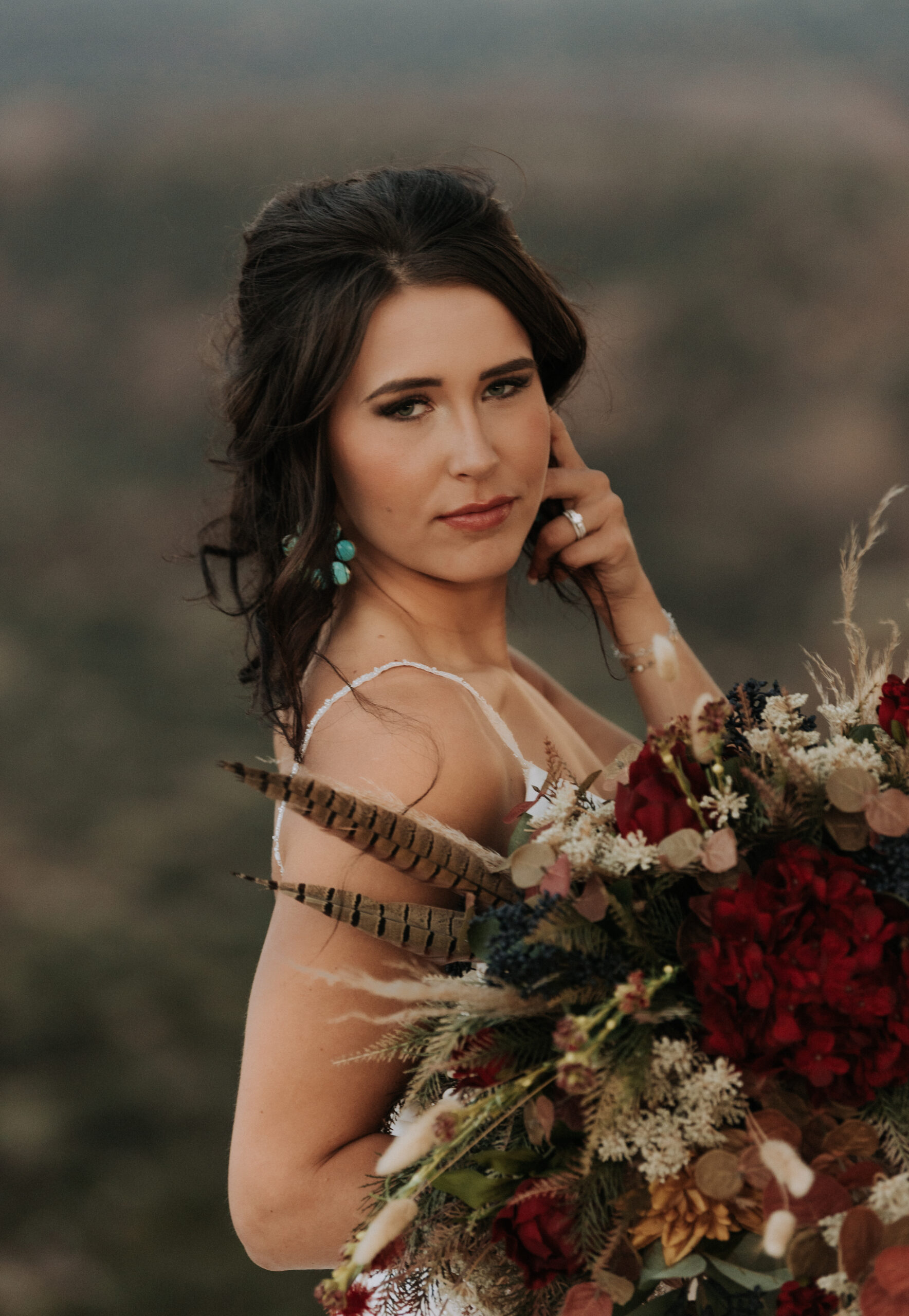 woman holding hair while looking at camera while holding wedding bouquet with background blurred, Texas bridal portrait photographer