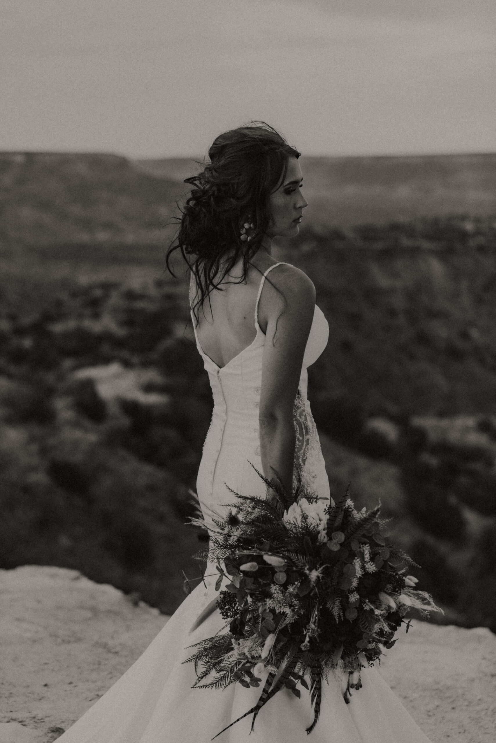 black and white photo of bridal portraits with bride holding bouquet down to the ground and looking away from camera, texas bridal portrait photographer, destination wedding photographer