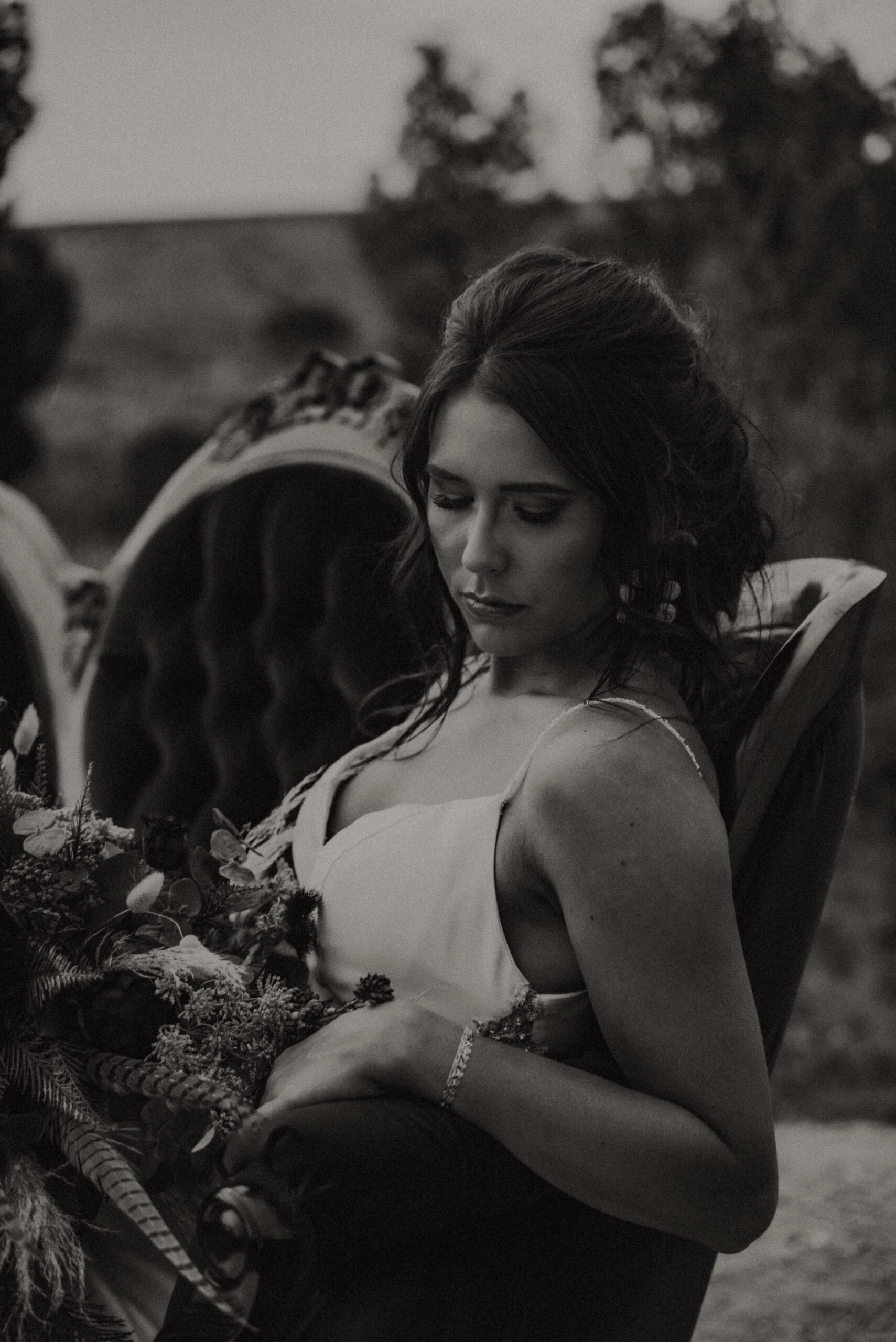 bride posing on settee while posing and holding wedding bouquet with trees in the background. Texas wedding photographer, bridal portrait photography