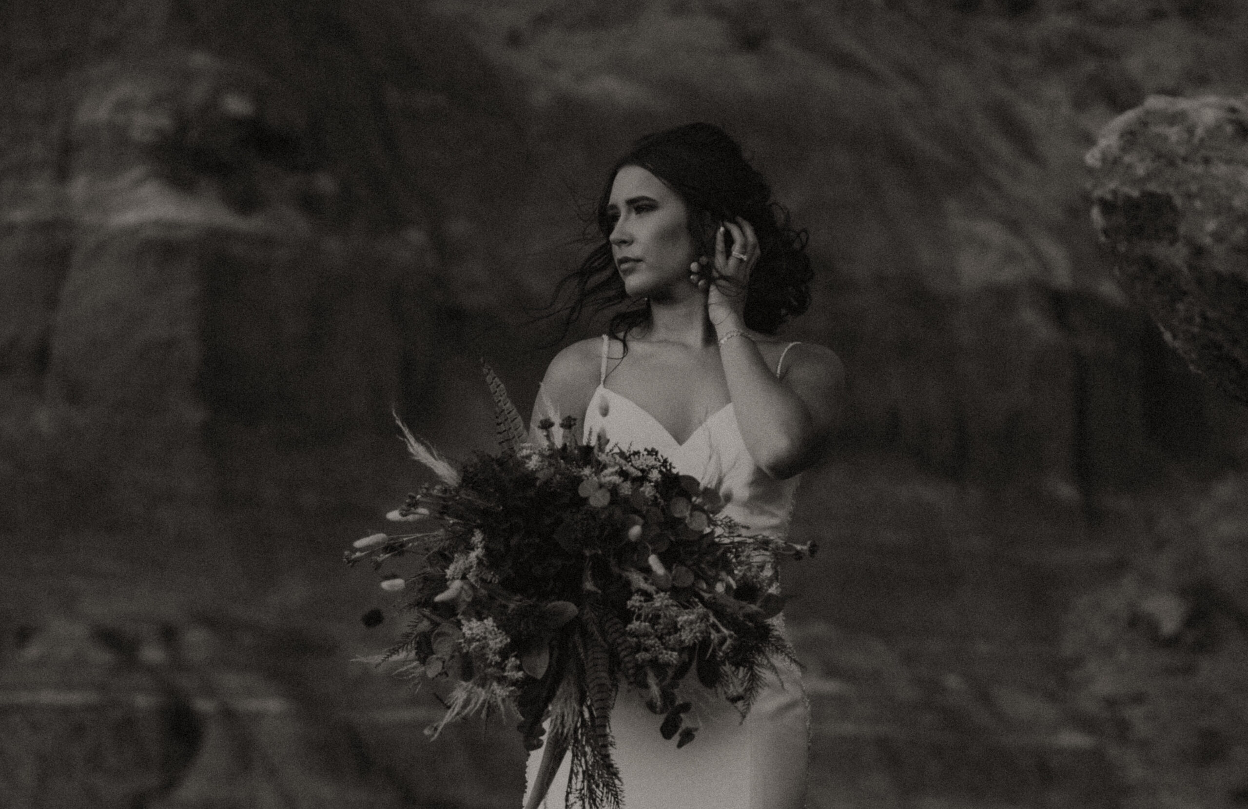 woman holding hair while looking away from camera while holding wedding bouquet and posing in the Texas Desert, bridal portraits, Texas wedding photography