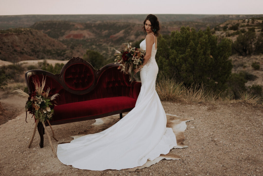 bride posing in front of the settee while holding the wedding bouquet and looking down at the ground, texas wedding photographer, bridal portrait photo sessions